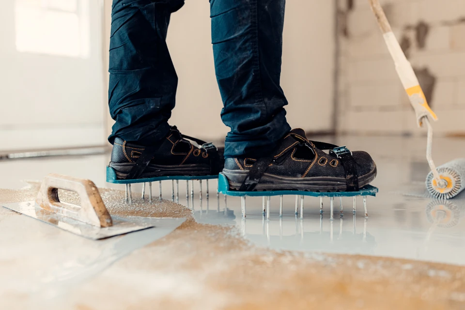 Gros plan professionnel montrant une main d'artisan appliquant une résine liquide décorativeavec une spatule ou un outil spécialisé sur une surface, avec la résine formant un fini lisse et brillant révélant des reflets ou un effet de couleur riche et moderne. La surface en arrière-plan doit montrer le rendu fini impeccable, haut de gamme et distinctif d'une résine décorative premium. Lumière naturelle ou professionnelle mettant en évidence la qualité et l'aspect haut de gamme du produit appliqué.