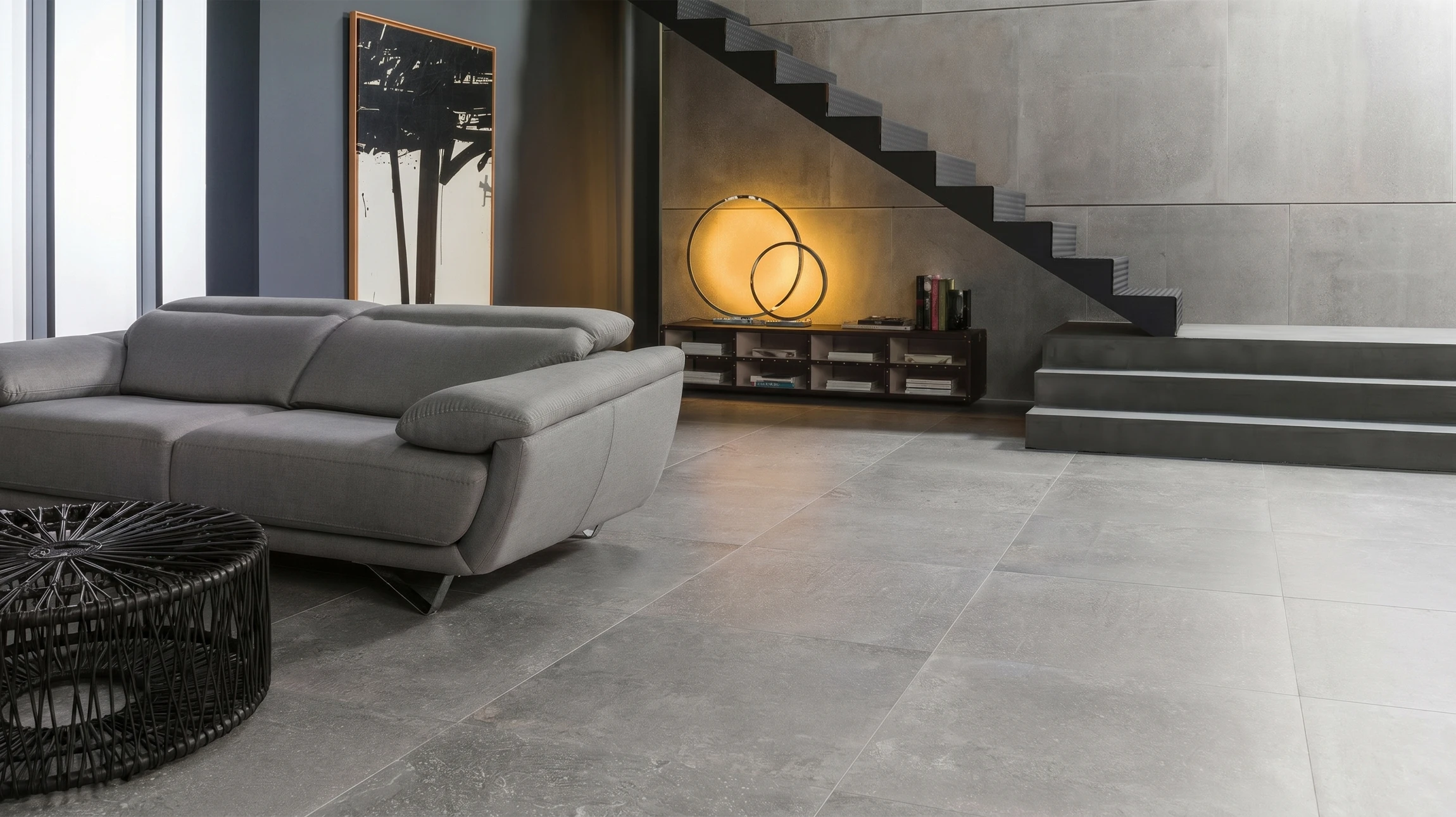 Photographie en plongée ou légèrement en contre-plongée d'un intérieur résidentiel haut de gamme mettant en avant un sol en carrelage grand format moderne, brillant et impeccable, posé de manière professionnelle. La composition doit valoriser la beauté et la qualité exceptionnelle du revêtement de sol, avec un éclairage naturel qui met en relief les textures et la finition premium. Le contexte peut être un living contemporain ou un espace ouvert, mais le focus principal doit absolument être sur la splendeur du sol lui-même pour illustrer l'expertise en revêtements de sol haut de gamme.